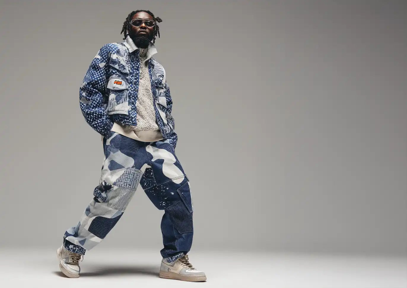 A man rocking an oversized denim jacket and matching baggy patchwork pants, perfectly embodying bold Y2K fashion aesthetics.