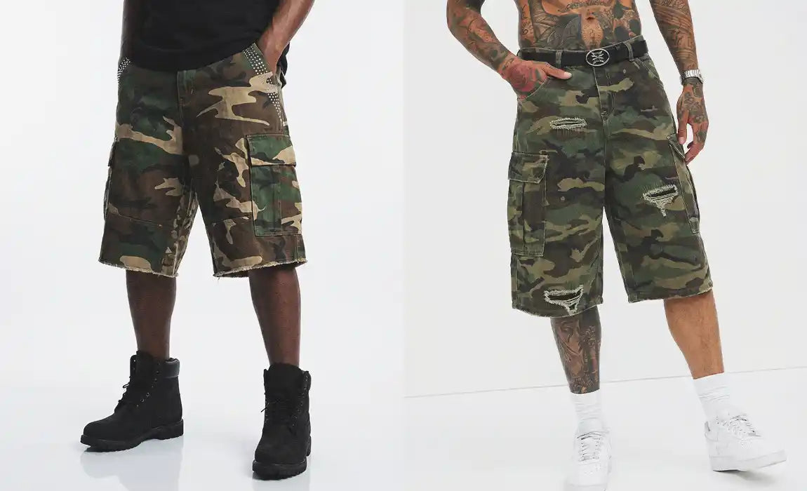 Close-up product view of two pairs of camo jorts showing cargo pocket details, studded accents, raw-cut hems, and distressed rip detailing
