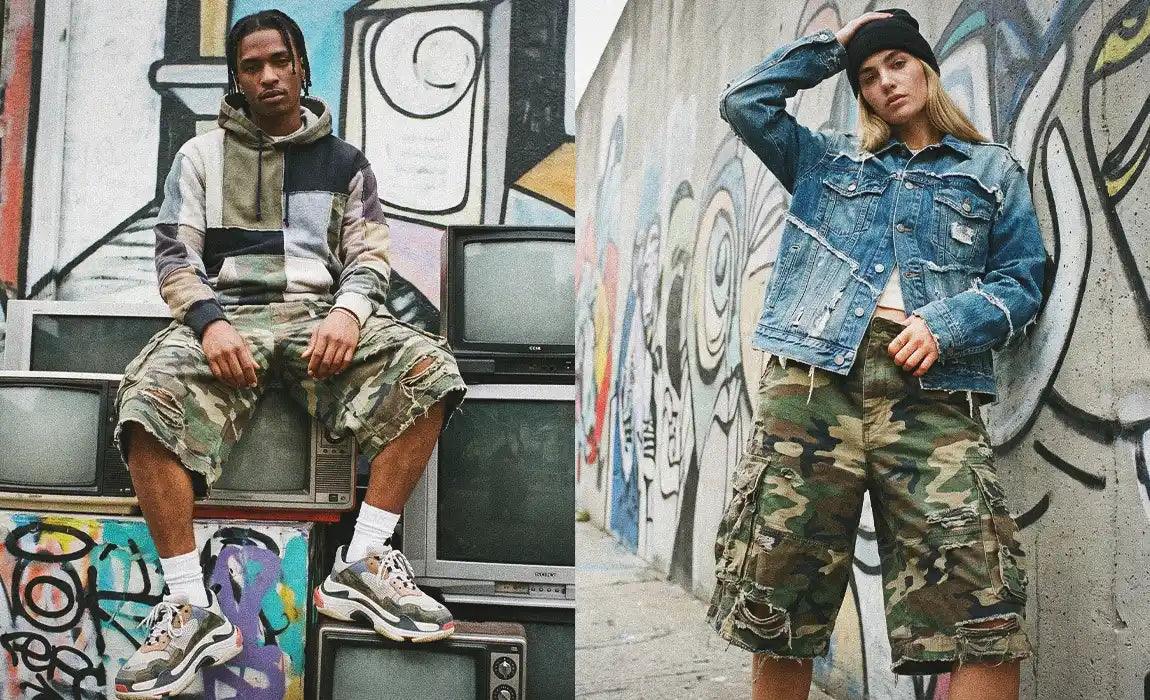Split editorial shot featuring a male model sitting on stacked vintage TVs in patchwork hoodie and baggy camo jorts, alongside a female model in denim jacket and oversized camo jorts against a graffiti wall