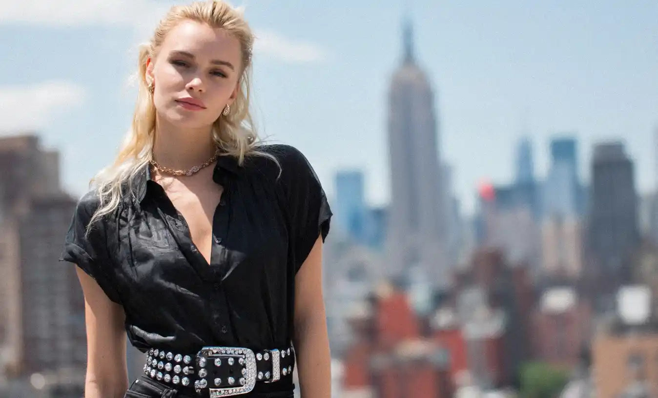 A woman in a black shirt is seen wearing a black rhinestone belt.