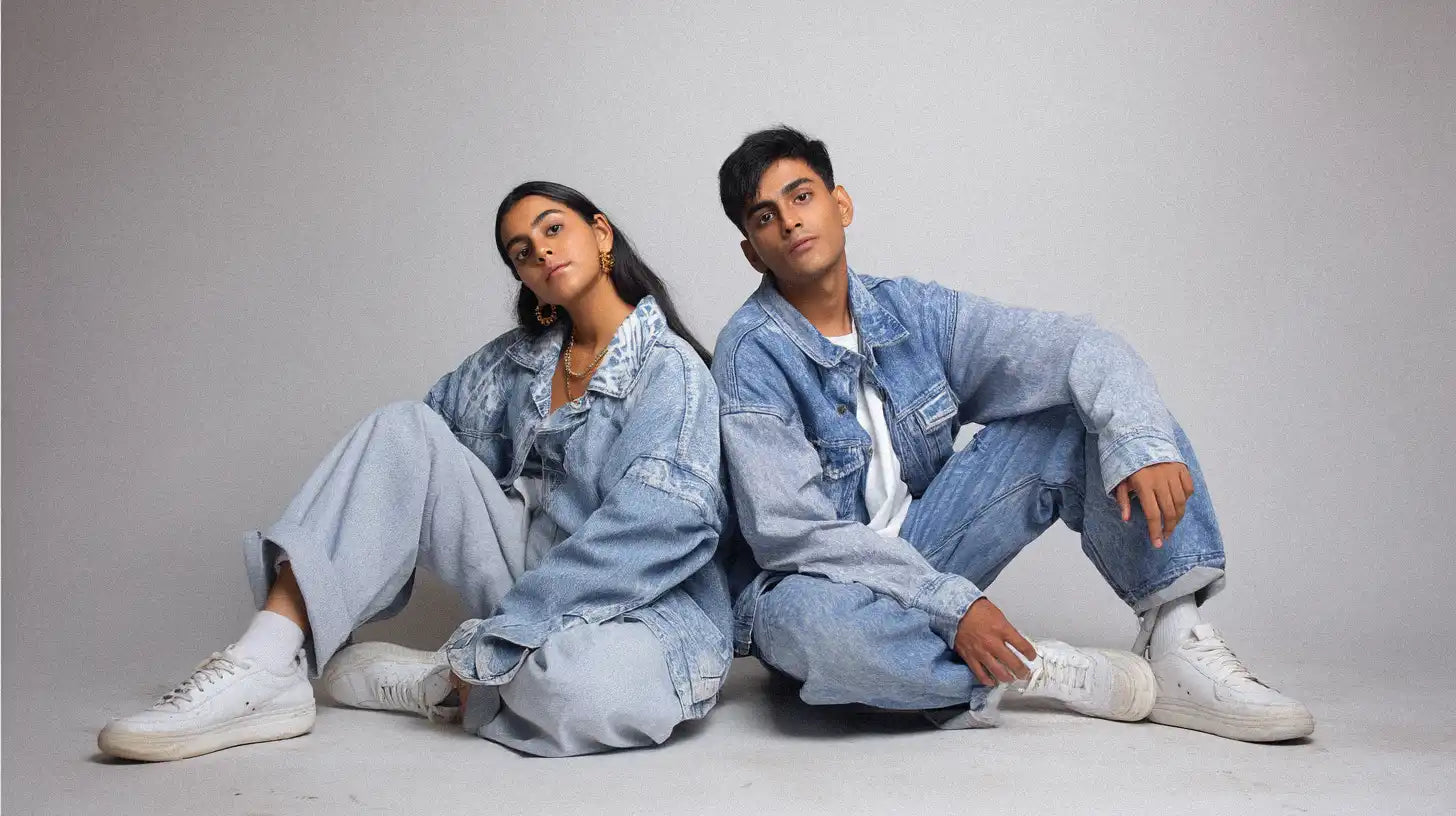 Duo in light wash denim outfits and sneakers, captured in a casual Y2K fashion studio look.