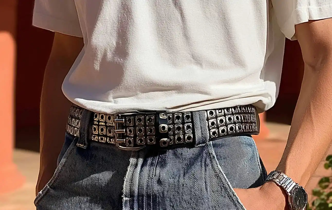 Double grommet black y2k belt with grid-style metal details, worn with washed blue denim.